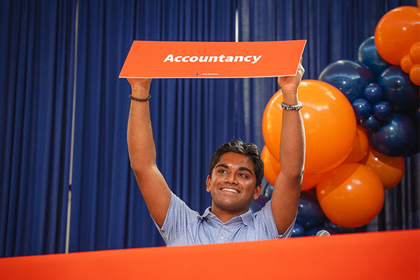 Gies Undergraduate Student Holding an Accountancy Sign to Declare Their Major
